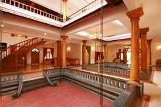 the inside of a building with columns, stairs and red carpeted flooring is shown