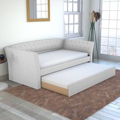 a white couch sitting next to a window on top of a carpeted floor in front of a mirror