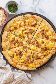 a pizza sitting on top of a pan covered in cheese and toppings next to a bowl of macaroni and cheese