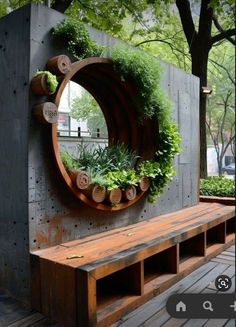 a wooden bench sitting under a mirror on the side of a building with plants growing in it