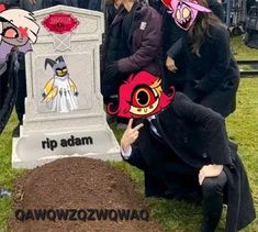 a group of people standing around a grave with paper hats on their heads and faces