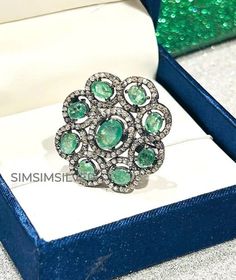 an emerald and diamond ring in a box