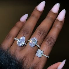 a woman's hand with two engagement rings on her fingers and one ring in the middle