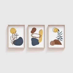 three framed artwork pieces hanging on the wall in front of a white wall, each with different shapes and colors