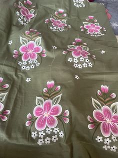 a green and pink floral print fabric with white flowers on the side, laying on top of a bed