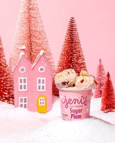 an ice cream cup with some cookies in it next to small houses and trees covered in snow