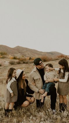 a group of people that are standing in the grass with one person holding a baby