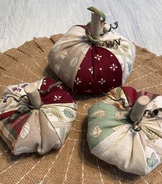 three fabric pumpkins sitting on top of a burlocked tablecloth covered surface