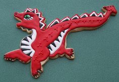 a cookie shaped like a lizard on top of a green surface with white and red icing