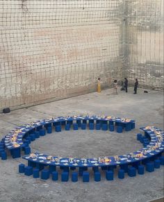 a large circular table with many blue containers on it in an enclosed area next to a wire fence