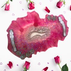 a pink and silver heart shaped tray with glitters on it, surrounded by rose petals