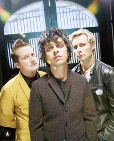 three young men standing next to each other in front of a window with bars on it