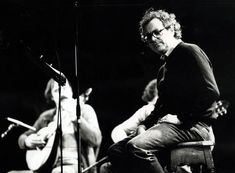 a man sitting on top of a chair next to a microphone and another person standing behind him