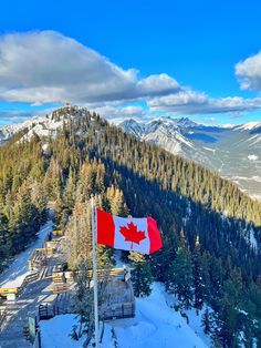 the canadian flag is flying high in the mountains