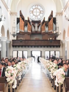 an aisle lined with pews filled with white and pink flowers