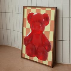 a red teddy bear sitting on top of a table next to a white tiled wall