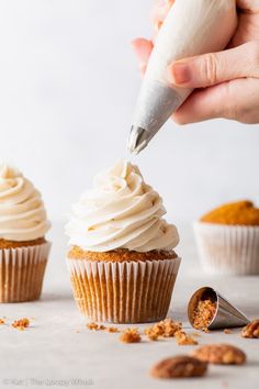 someone is decorating cupcakes with white frosting and cinnamon crumbs