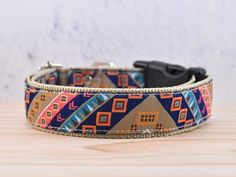 a colorful dog collar on a wooden table with a black cat sitting in the background