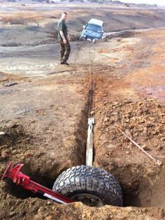 a man standing next to a truck on top of a dirt field near a pipe