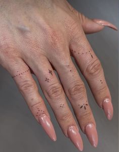 a woman's hand with black dots on it and a star tattoo on the middle finger