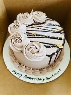 a birthday cake with white frosting and chocolate icing roses on it in a box