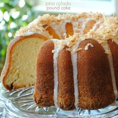 a bundt cake with white icing and coconut toppings on a glass plate