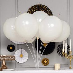 white balloons are floating in the air above a table with candles and other decorations on it