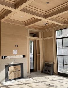 an empty room with wood paneling and large windows in the center, surrounded by construction materials