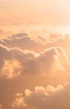 an airplane is flying through the clouds at sunset