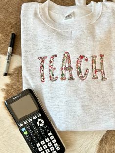 You will absolutely LOVE this this fun sweatshirt for your favorite educator! This beautiful embroidered appliqué sweatshirt will keep you cozy, warm and stylish for all of your busy days at school!💛  Fabric options are either pink floral or blue floral as shown above, be sure to include which you would like! Embroidered Applique Sweatshirt, Applique On Sweatshirt, Embroidered School Sweatshirt, Fall School Tops With Embroidered Logo, Fall School Tops With Embroidery, Embroidered Tops For School In Fall, School Spirit Embroidered Cotton Sweatshirt, Cotton Sweatshirt With School Spirit Embroidery, Cotton Sweatshirt With Embroidered Text For School