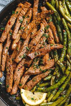 steak and asparagus in a skillet with lemon wedges