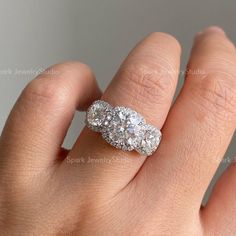 a woman's hand with a diamond ring on top of her finger and an oval shaped diamond in the middle