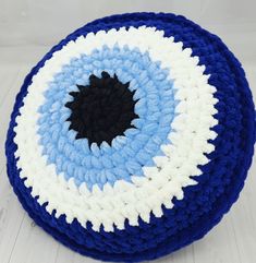 a blue and white crocheted poufce with a black center on it