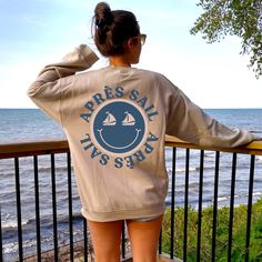 Apres-sail into summer in our cute and trendy Happy Face Après Sail sweatshirt. It's the perfect sweatshirt for spring break, cool summer evenings, boating excursions, cruise vacations or just enjoying a sunset. This sweatshirt features both front and back printed design.  Après Sail Sweatshirt, Happy Face Shirt, Trendy Sweatshirt, Sailing Shirt, Nautical Gift, Preppy Sweatshirt, Beach Shirt, Boat Vacation A sturdy and warm sweatshirt bound to keep you warm in the colder months. A pre-shrunk, cl Sailing Apparel, Nautical Cotton Tops For Vacation, Nautical Style Cotton Tops For Vacation, Cotton Nautical Tops For Vacation, Casual White Top For Sailing, Casual White Tops For Sailing, Casual Sail Colored Top With Graphic Print, Casual Sail-colored Top With Graphic Print, Casual Summer Tops For Sailing