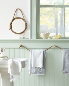 towels are hanging on the clothes line in front of a window with a mirror above it