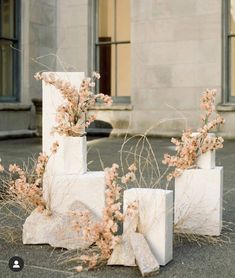 four cement blocks with flowers growing out of them in front of a large stone building