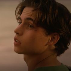 a close up of a person wearing a green shirt and looking off into the distance