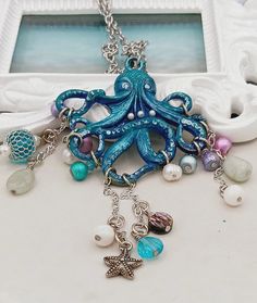 Ookie the octopus is dripping with treasures from the sea. He hangs on an 18 inch stainless steel chain and has a lobster clasp. Unique Adjustable Charm Necklace, Starfish Charm Metal Necklace For Gift, Whimsical Pendant Charm Necklaces With Lobster Clasp, Metal Necklace With Starfish Charm For Gift, Whimsical Dangle Jewelry With Lobster Clasp, Ocean-inspired Jewelry With Dangling Charms For Gifts, Whimsical Dangle Necklaces With Lobster Clasp, Adjustable Ocean-inspired Charm Necklace With Lobster Clasp, Octopus Jewelry