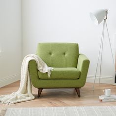 a green chair sitting on top of a hard wood floor next to a white wall