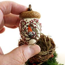 a hand holding a tiny bird on top of a nest