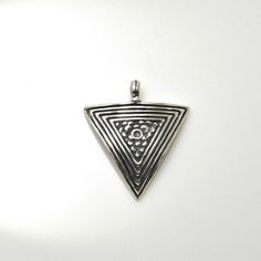 a silver triangle shaped pendant on a white background