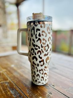 a white and brown leopard print coffee cup sitting on top of a wooden table