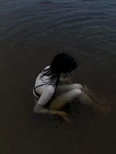 a woman is sitting in the water with her legs spread out and she is bent over