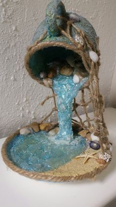 a white toilet sitting next to a wall covered in sand and sea shells on top of it