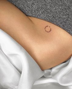 a woman's stomach with the word love written on it and a circle tattoo