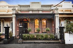 an old brick house with wrought iron fence and gated entryway leading to the front door