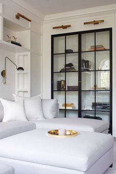 a living room with white furniture and shelves