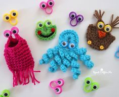 crocheted toys are arranged on a white surface with scissors and eyeballs in the shape of animals