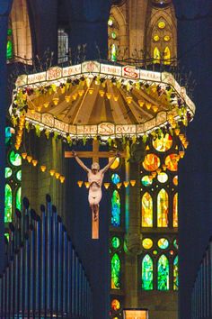 a person on a cross in front of a church with stained glass windows and lights