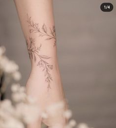 a woman's foot with a tattoo on it and flowers in the foreground